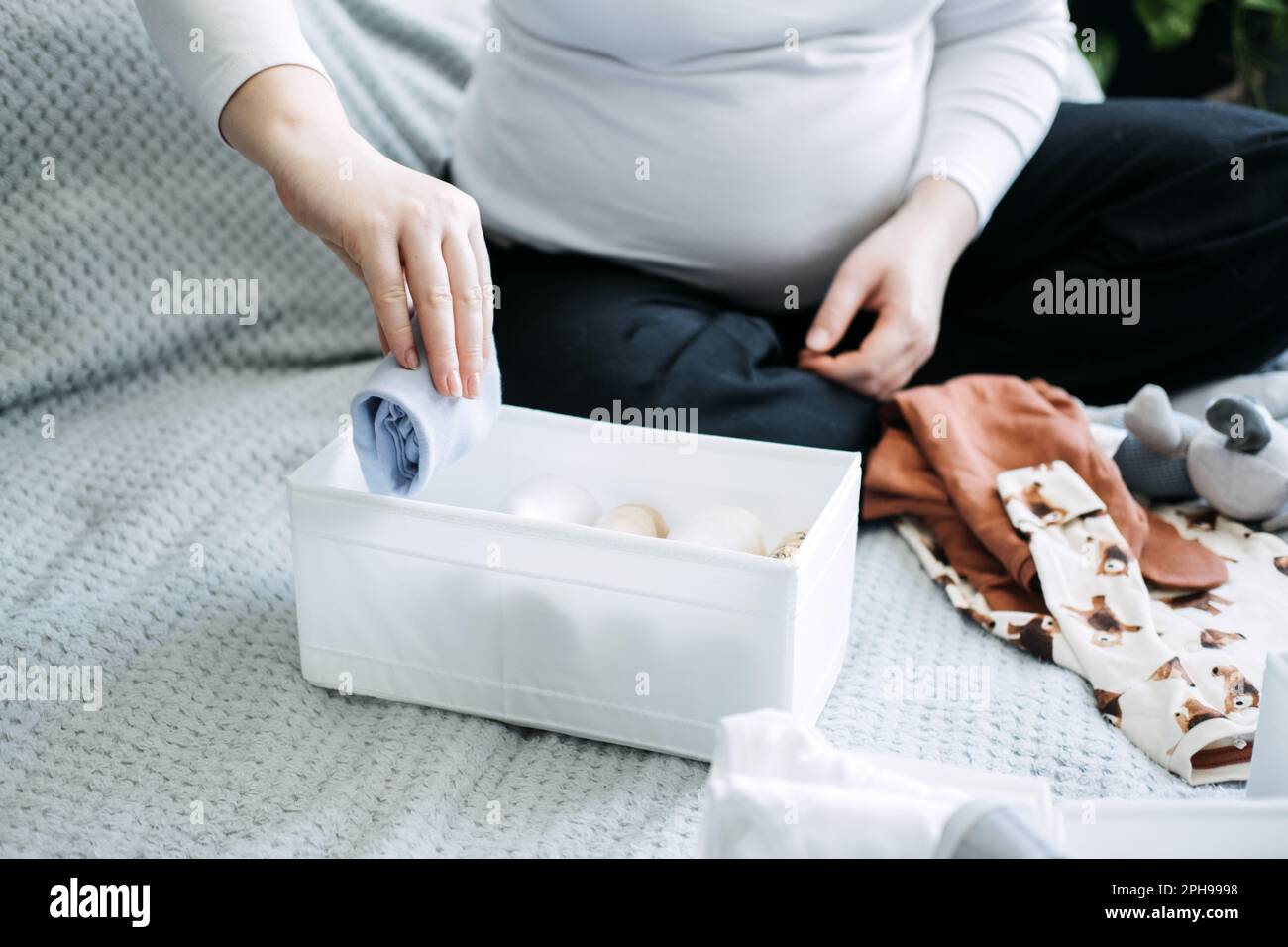 How to Organize Newborn Baby Clothes. Pregnant woman Using ornament