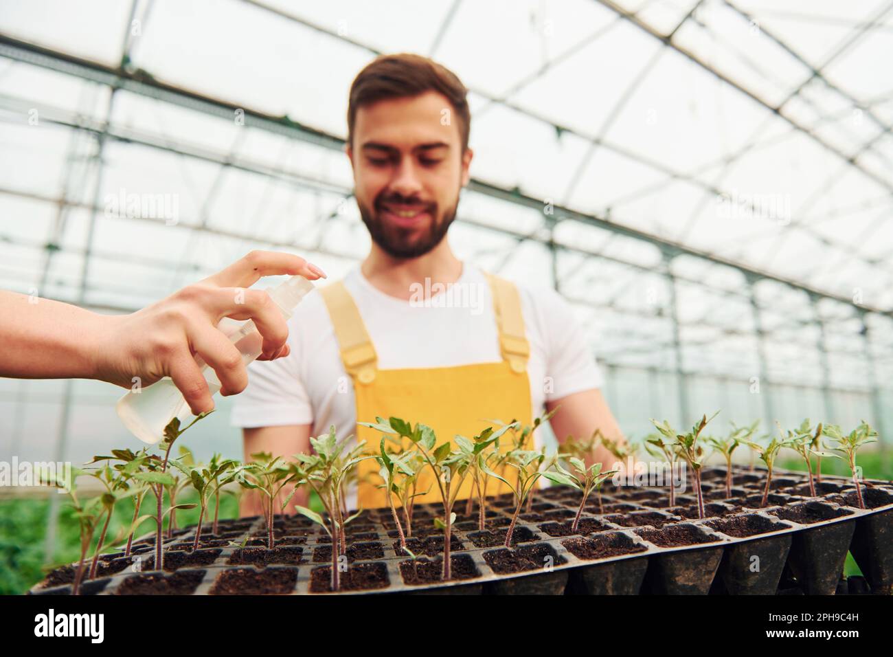 Woman's hand watering plants. With black stand in hands. Young
