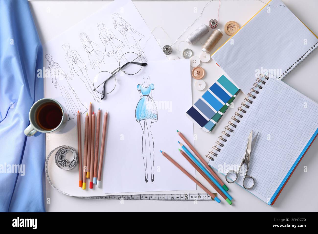 Sketches of clothes and different stuff on white table, flat lay 
