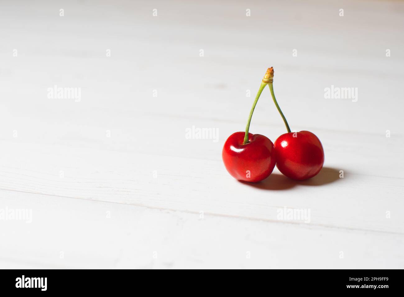 Two cherries on a white table Stock Photo