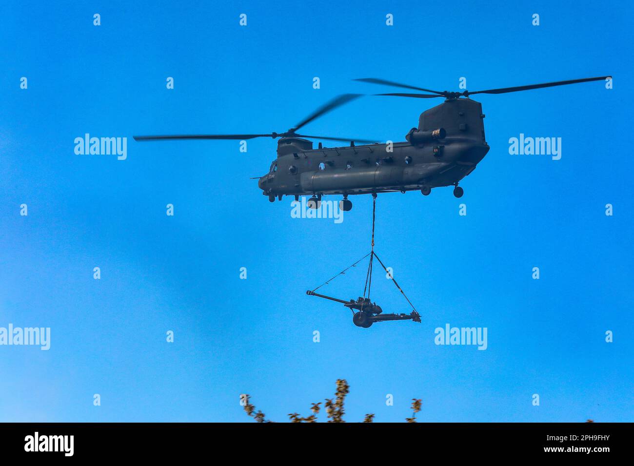 Royal Air Force operated Boeing CH47 Chinook (ZH897) airborne with a 105mm field gun or the Royal Artillery. Stock Photo
