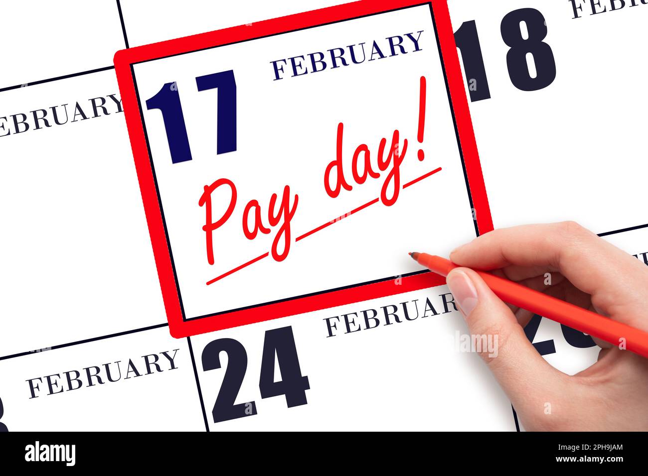17th day of February. Hand writing text PAY DATE on calendar date February 17 and underline it. Payment due date.  Reminder concept of payment. Winter Stock Photo