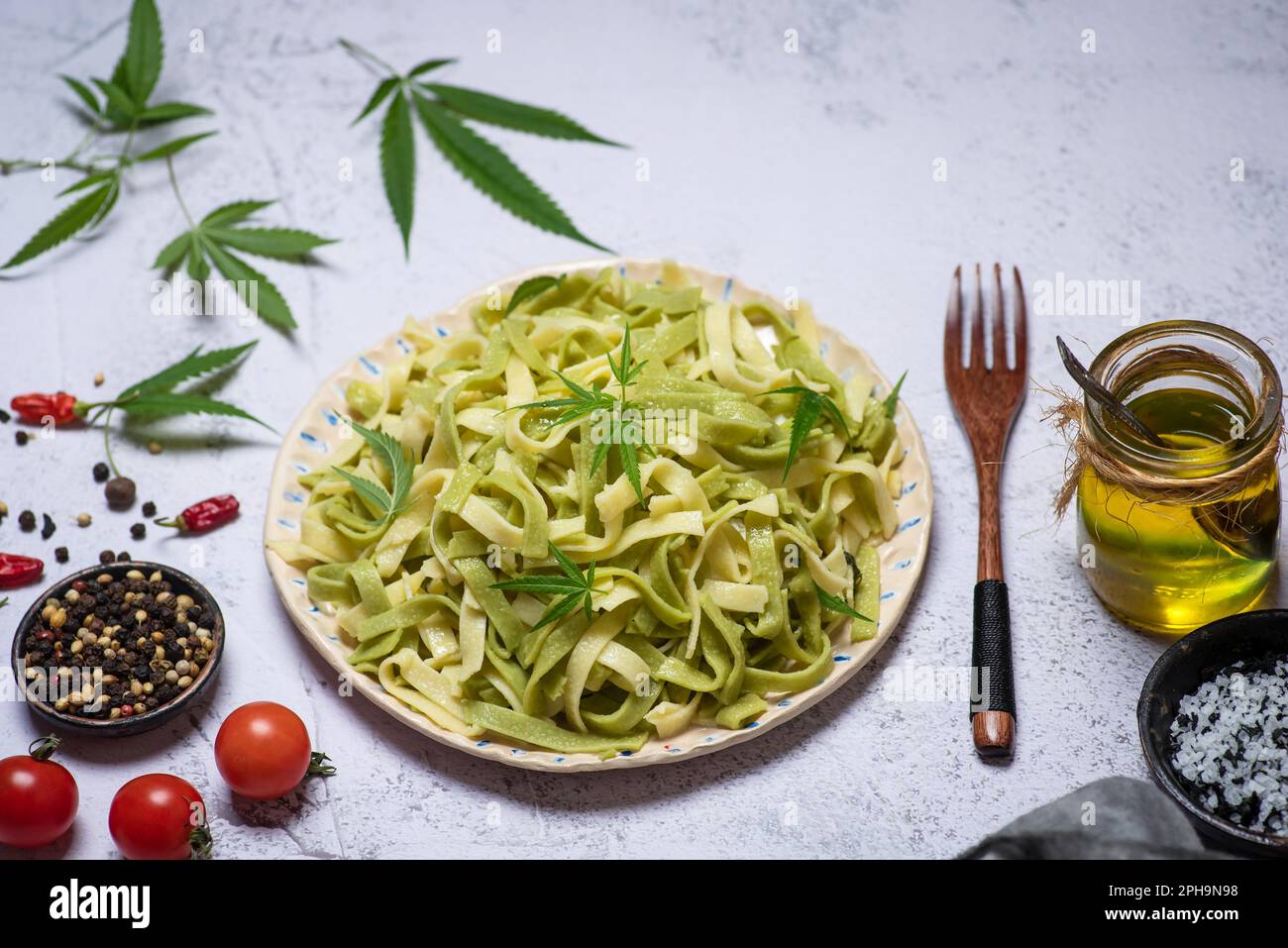 Italian traditional pasta Tagliatelle with cannabis leaves in a ceramic bowl on a white background top view Stock Photo