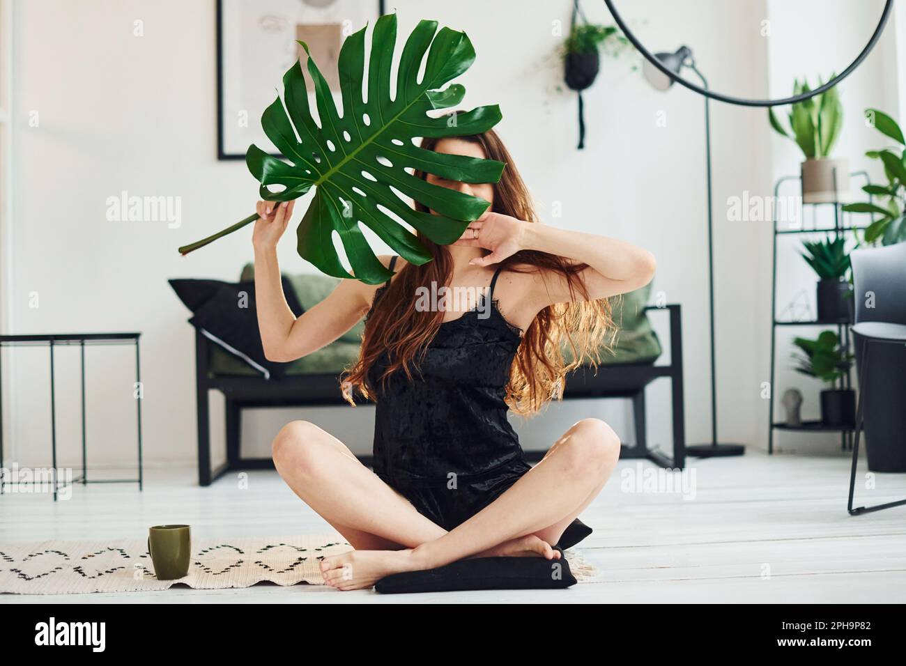 Young woman in pajamas sitting on the floor indoors at daytime and ...