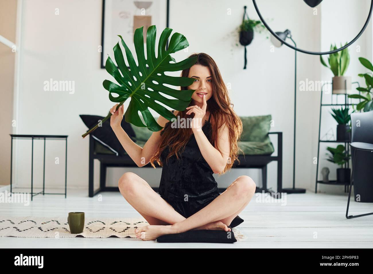 Young woman in pajamas sitting on the floor indoors at daytime and ...