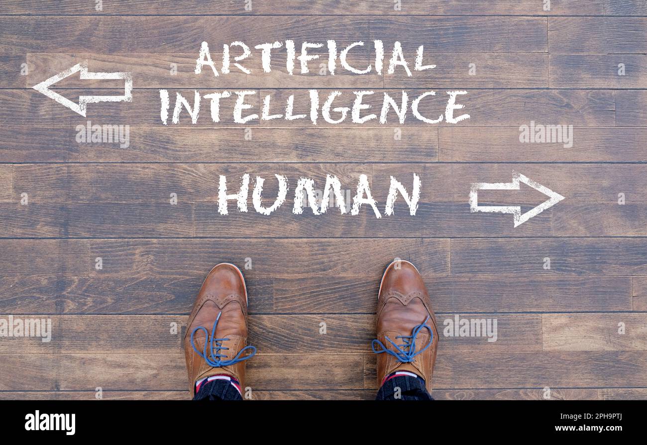 Man looking down at the words Artificial Intelligence - AI - and Human chalked onto the floor Stock Photo