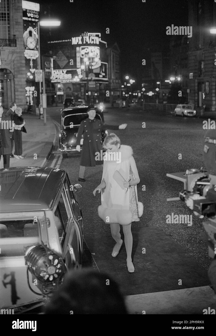 London. circa.1967. A photograph of Mia Farrow with an Austin Mini Countryman estate car, outside the Café Royal, Regent Street in Piccadilly, London, taken behind the scenes during the filming of the neo-noir British spy movie, ‘A Dandy in Aspic’. The film was directed by Anthony Mann. Stock Photo