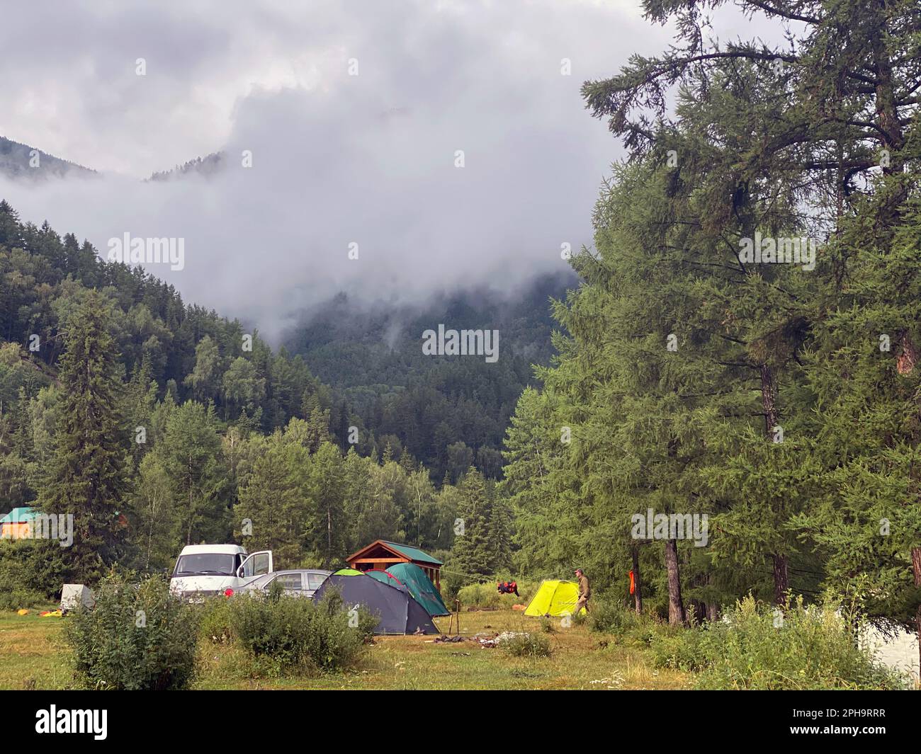 Places for rest with cottages and tents with cars of tourists near the river in Altai near the mountains Stock Photo