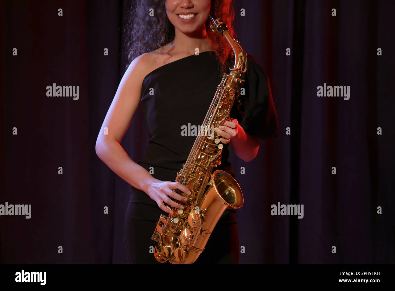 African American woman with saxophone on dark background, closeup Stock Photo