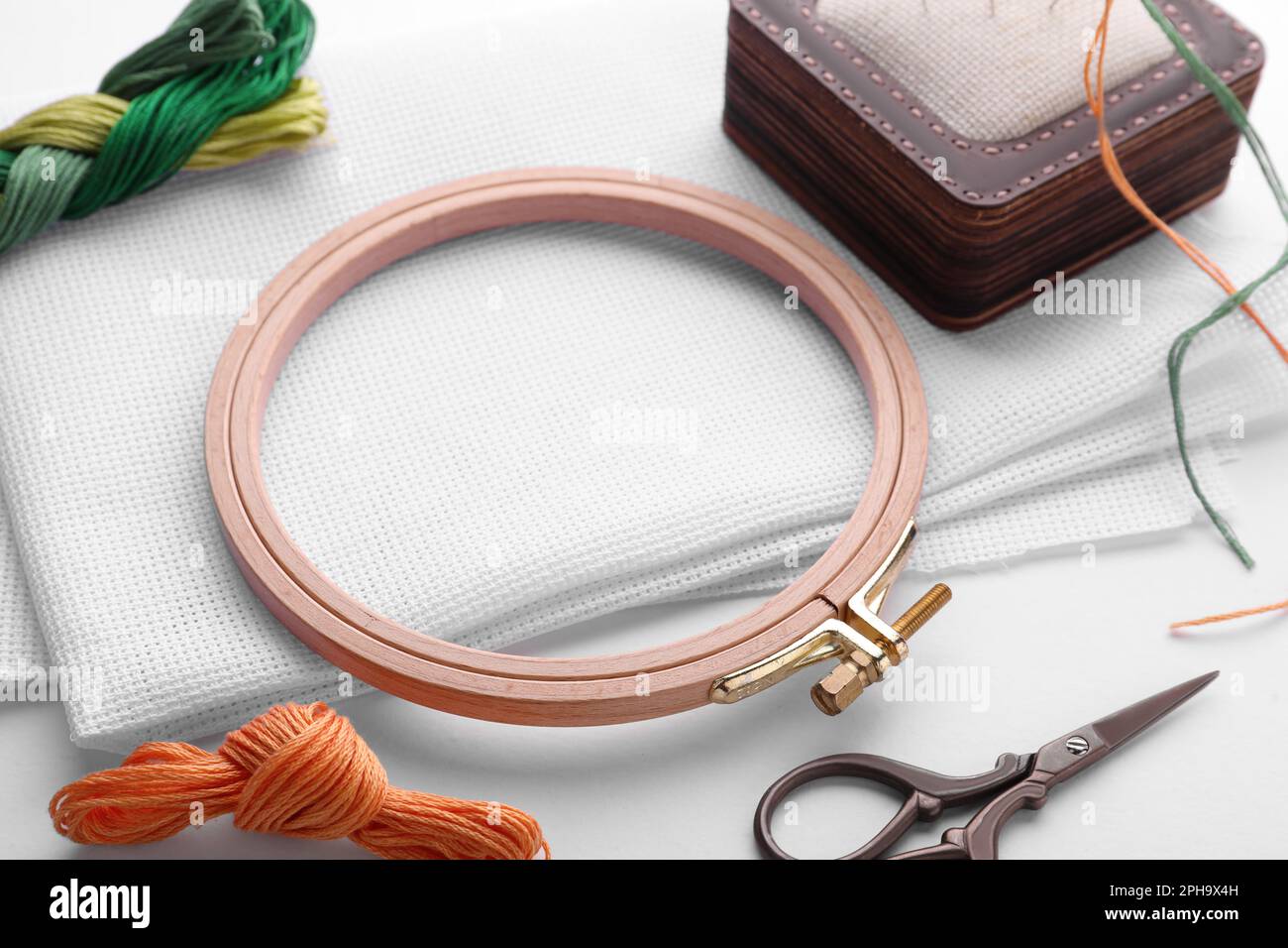 Embroidery hoop and multicolored accessories on white linen canvas with  spools of thread, needle and scissors Stock Photo - Alamy