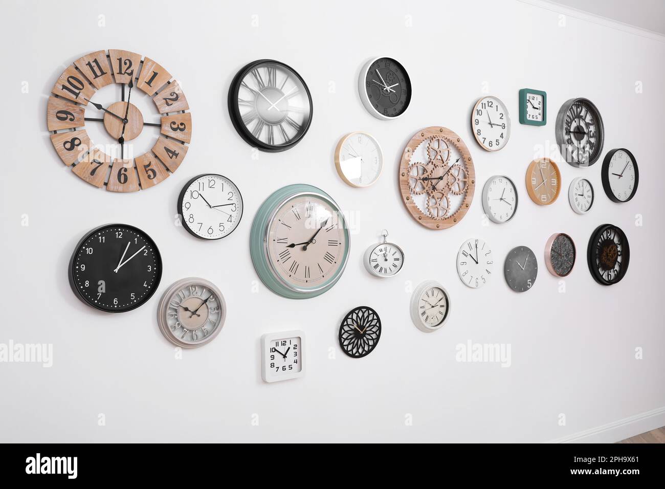 Collection of different clocks hanging on white wall Stock Photo Alamy