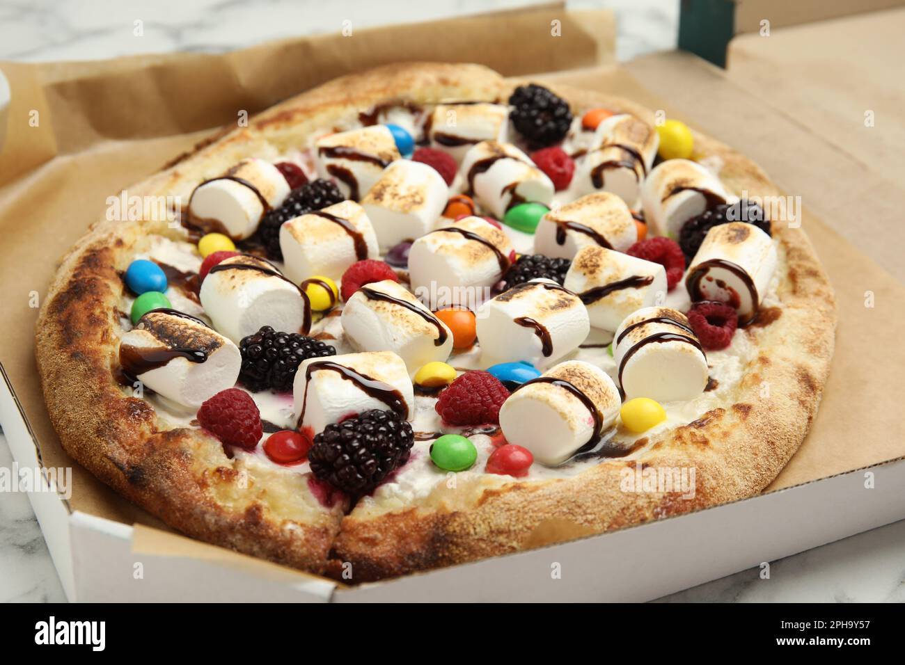 https://c8.alamy.com/comp/2PH9Y57/tasty-sweet-pizza-with-berries-marshmallows-and-candies-in-cardboard-box-on-table-closeup-2PH9Y57.jpg