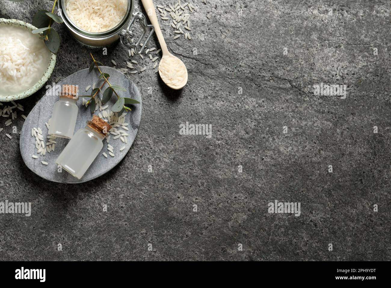 Flat lay composition with rice water on grey table. Space for text ...