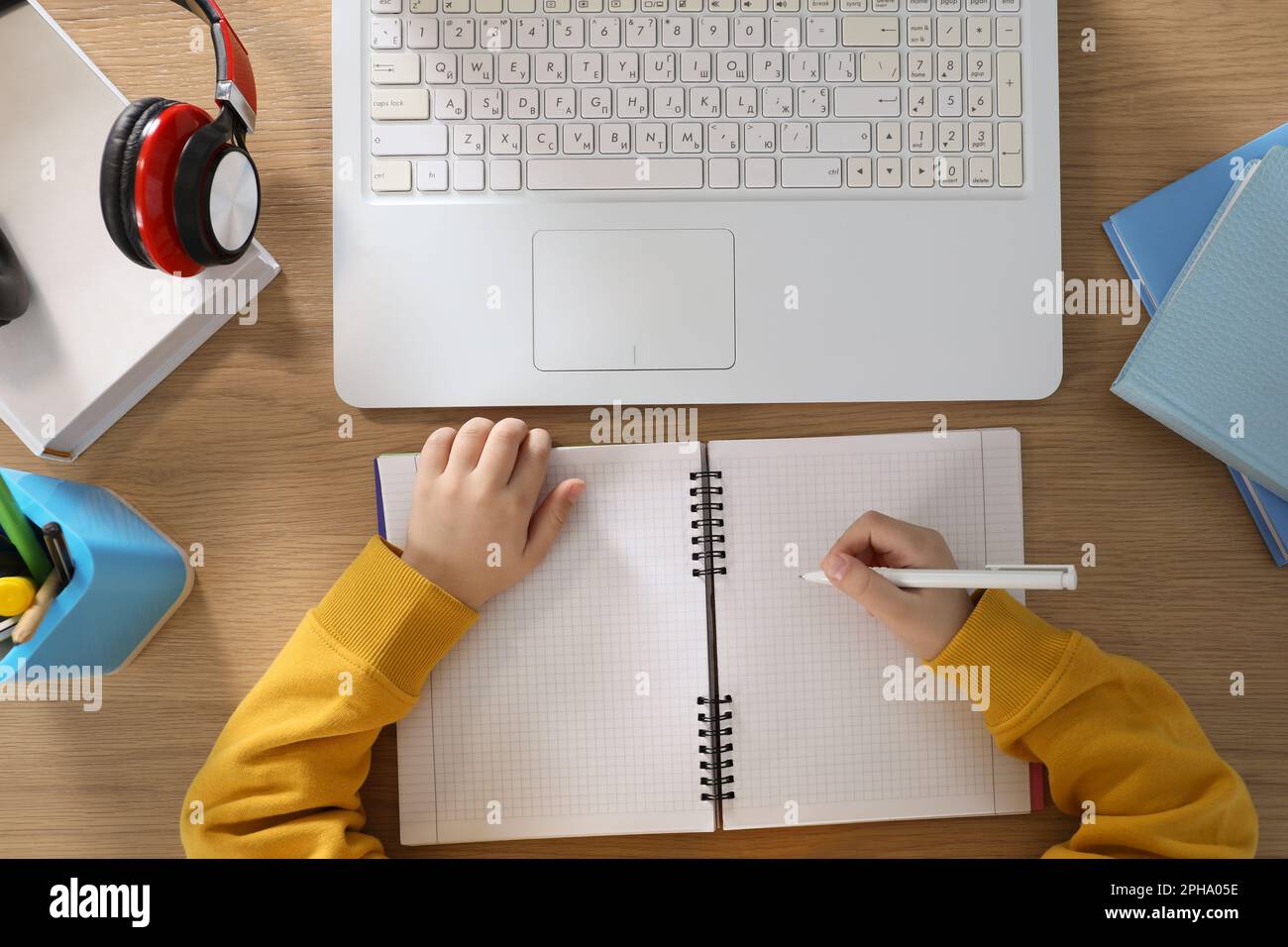 Cute little boy with modern laptop studying online at table, top view ...