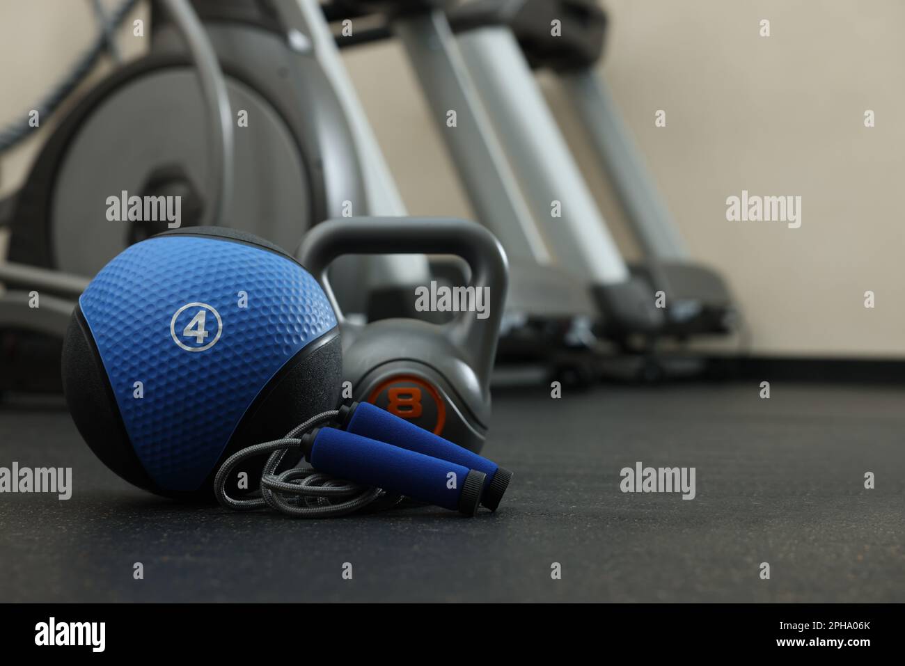 Blue medicine ball, kettlebell and skipping rope on floor in gym, space
