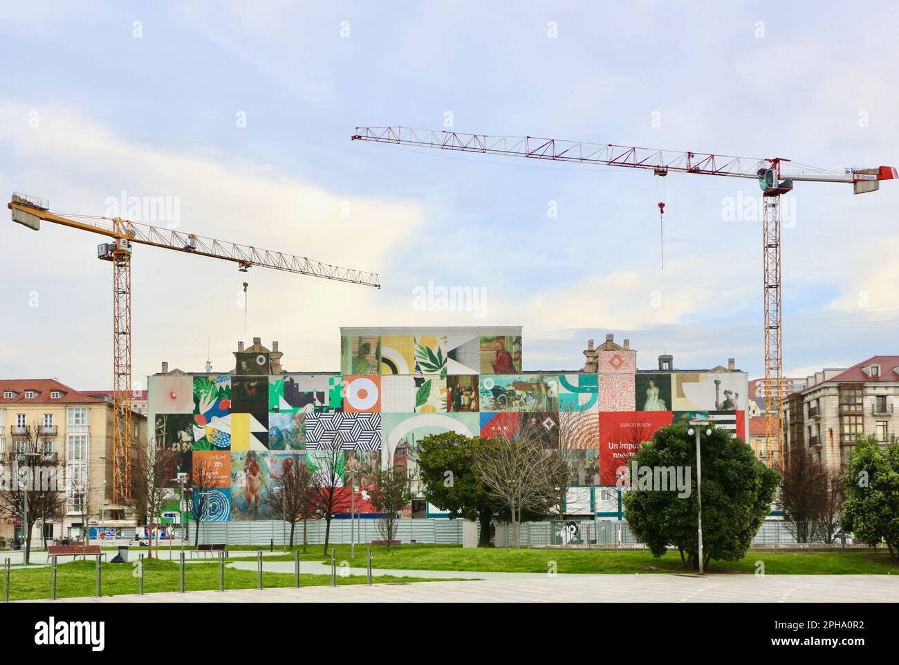 The old headquarters of Santander bank undergoing a repurposing into a museum with tower cranes and covered with graphics Santander Cantabria Spain Stock Photo