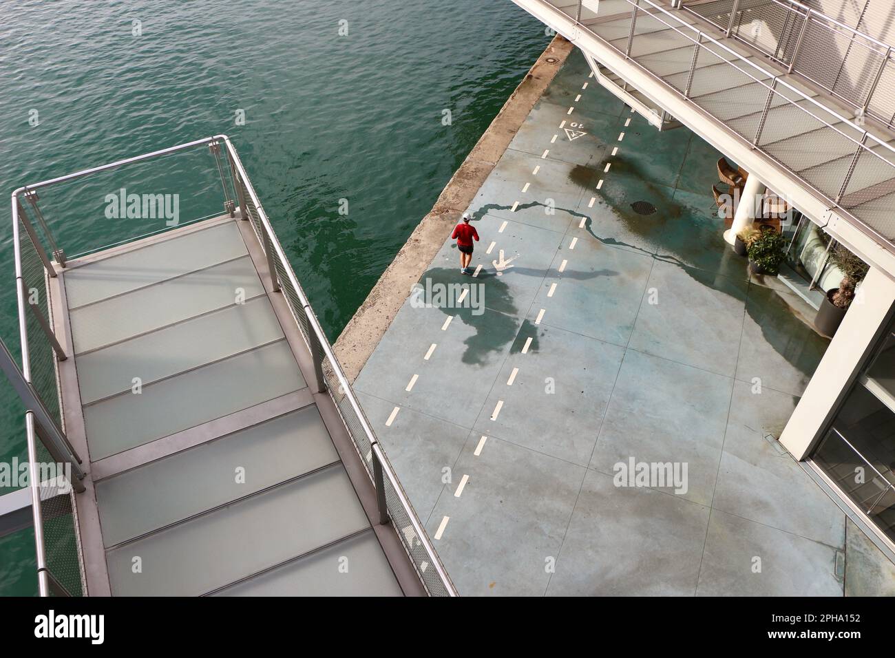 Lone male jogger seen from above running alongside the bay of Santander Cantabria Spain under the Botin Centre arts centre on a sunny spring morning Stock Photo