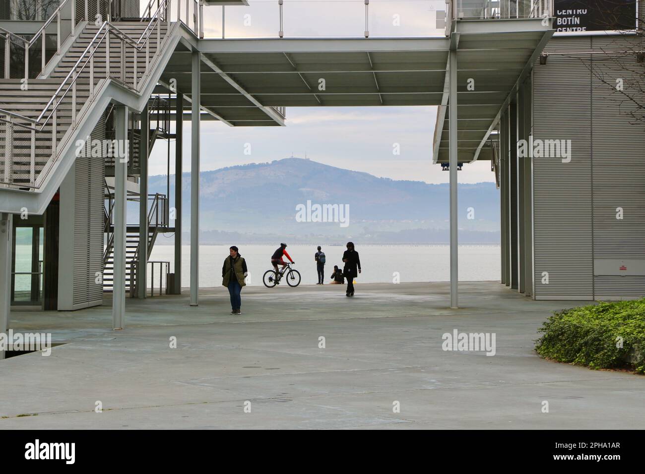 A cyclist and people passing by the Botin Arts Centre next to the bay on a calm spring morning Maritime Walk Santander Cantabria Spain Stock Photo