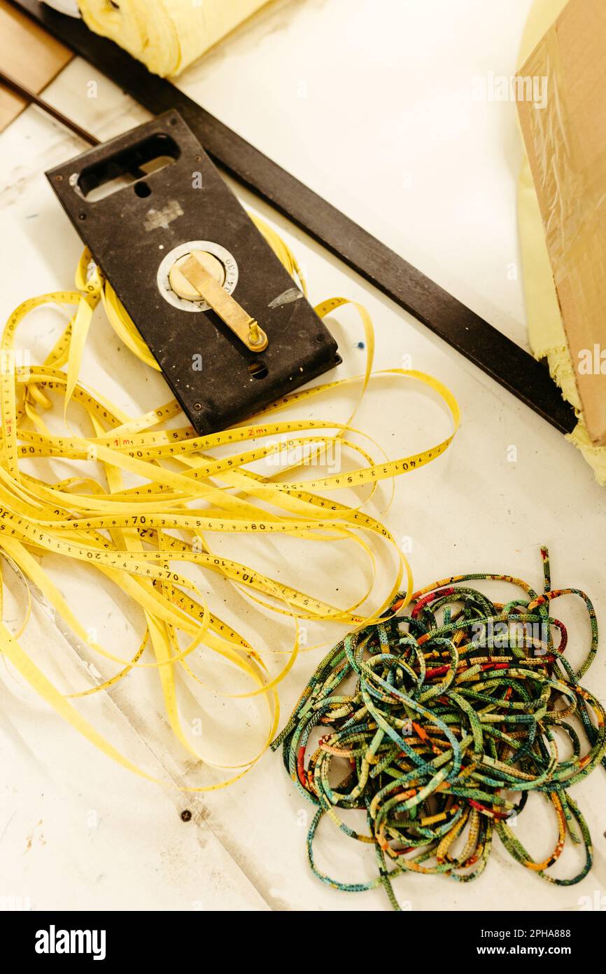 A close up shot of a yellow measuring tape lying near a vibrant multi-colored rope Stock Photo