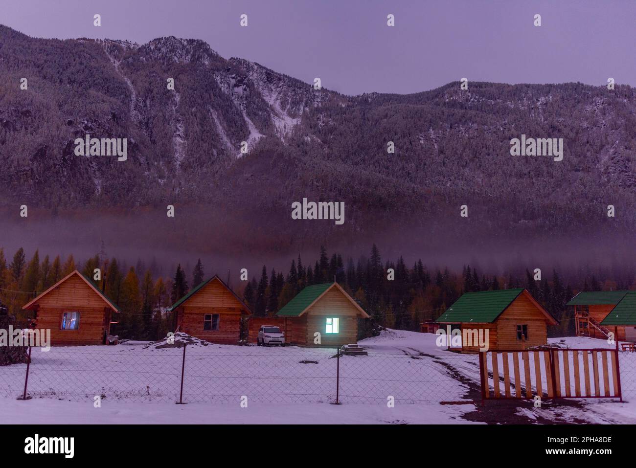 Altai, Russia - October 02, 2022 A Honda HRV brand car stands by vacation houses with a luminous window near a forest under a mountain with fog and sn Stock Photo