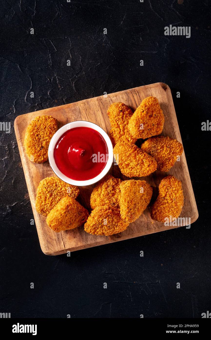 Chicken nuggets with bbq sauce on a black slate background, top shot. A