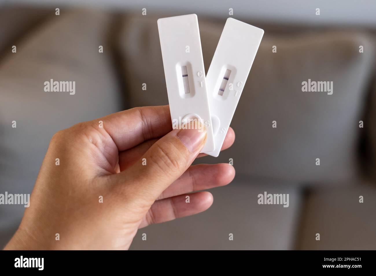Hand holding both the positive and negative test results of an antigen