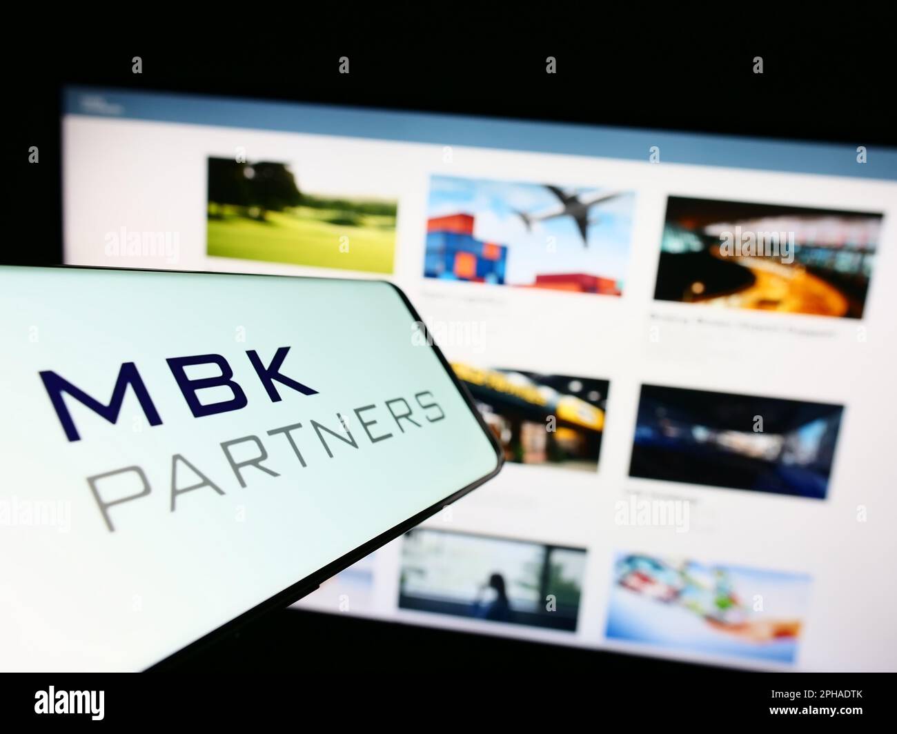 Smartphone with logo of Korean investment company MBK Partners Ltd. on screen in front of website. Focus on center-left of phone display. Stock Photo