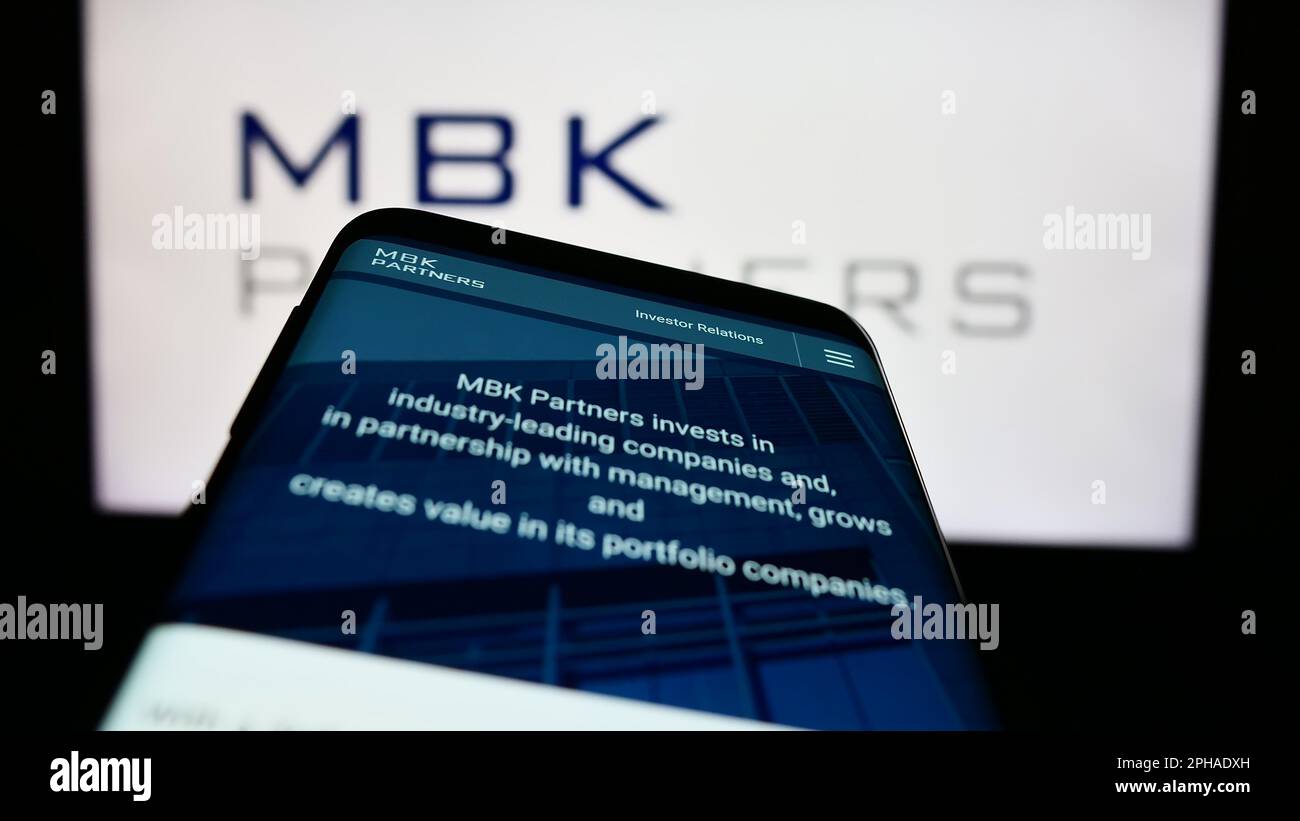 Mobile phone with website of Korean investment company MBK Partners Ltd. on screen in front of business logo. Focus on top-left of phone display. Stock Photo