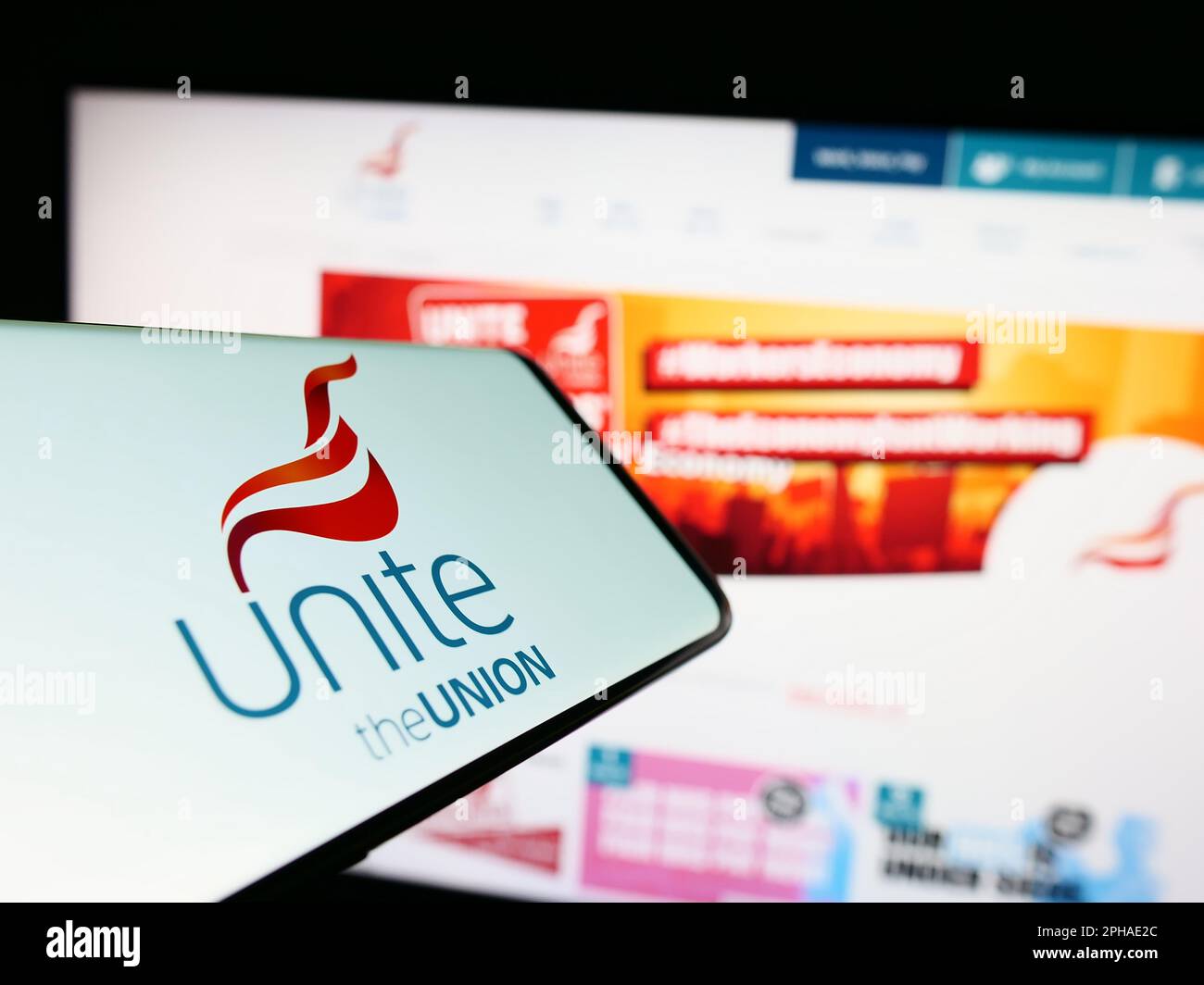 Mobile phone with logo of British trade union Unite the Union on screen in front of website. Focus on center-right of phone display. Stock Photo