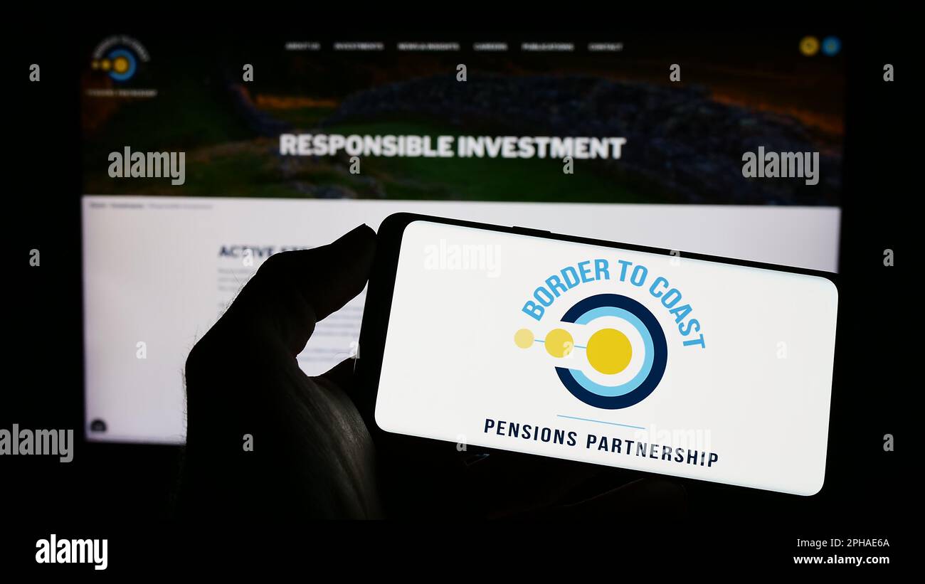 Person holding cellphone with logo of British Border to Coast Pensions Partnership on screen in front of webpage. Focus on phone display. Stock Photo