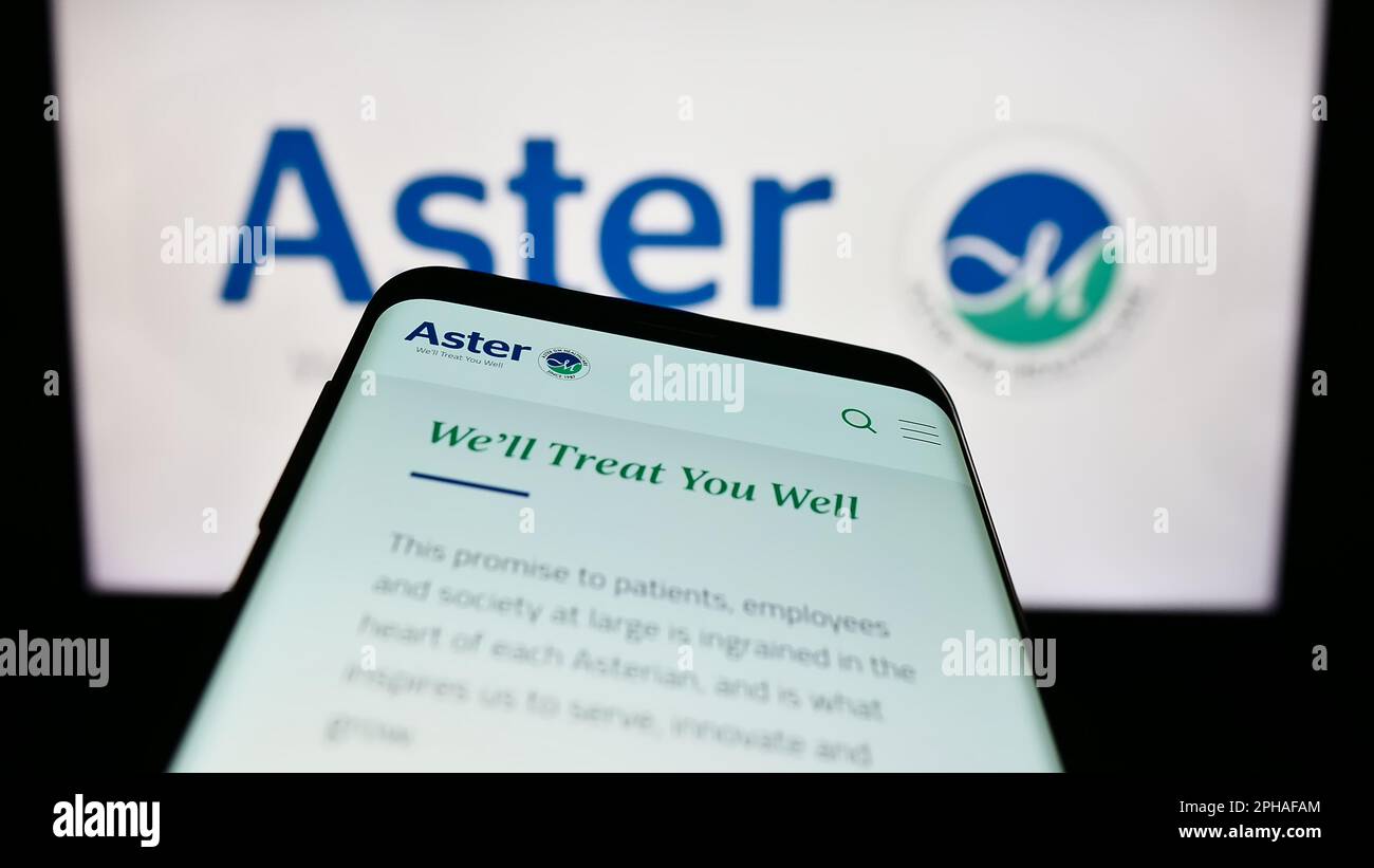 Smartphone with website of health company Aster DM Healthcare Limited on screen in front of business logo. Focus on top-left of phone display. Stock Photo