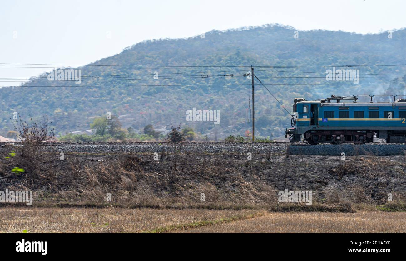 A train running in Chota Nagpur Plateau region in Jharkhand against mountain in the background. Stock Photo