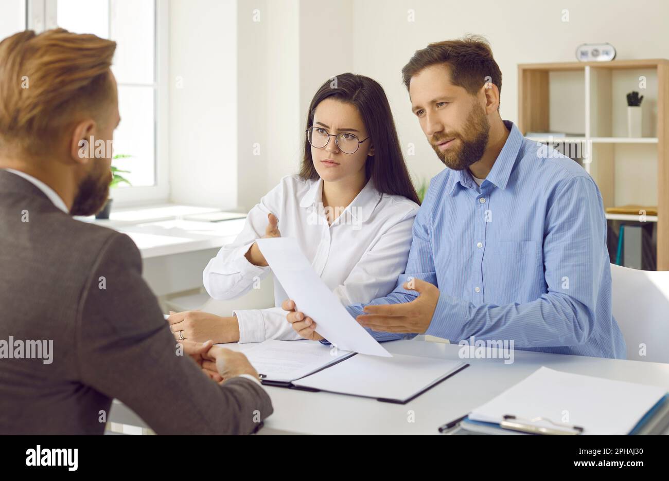 Angry clients having misunderstanding while talking about business contract with manager Stock Photo