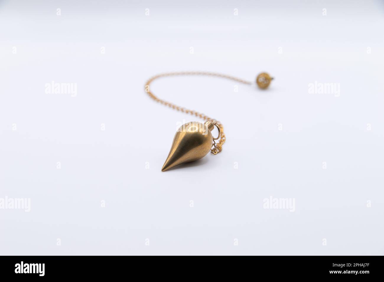 Brass pendulum on chain isolated on white background. Stock Photo