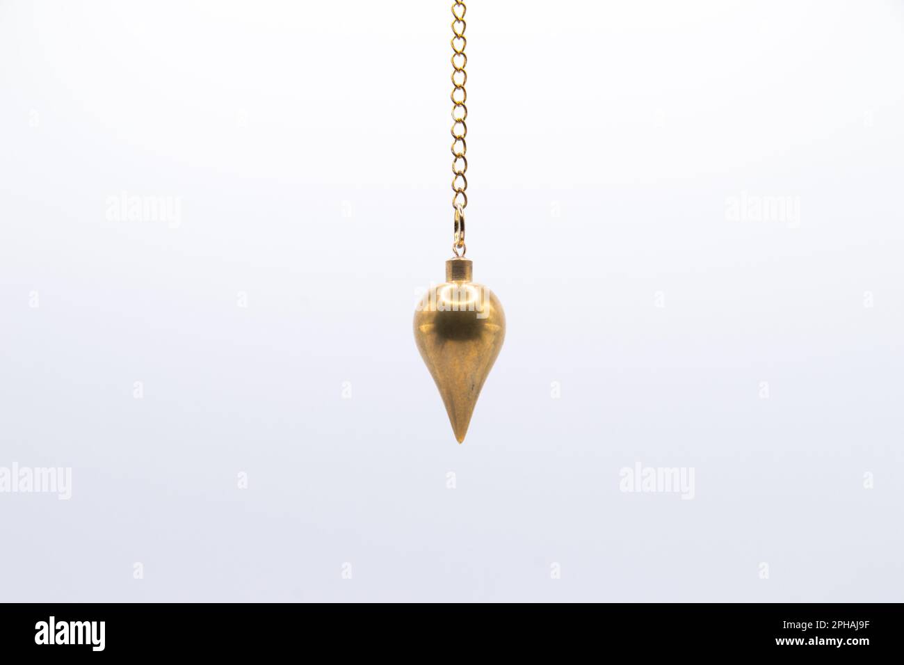 Brass pendulum on chain isolated on white background. Stock Photo