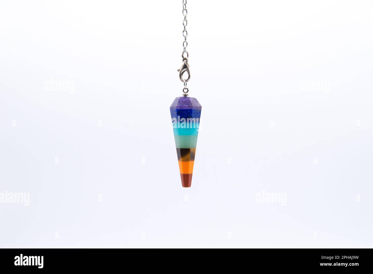 Seven Chakra color crystal pendulum on chain isolated on white background. Stock Photo
