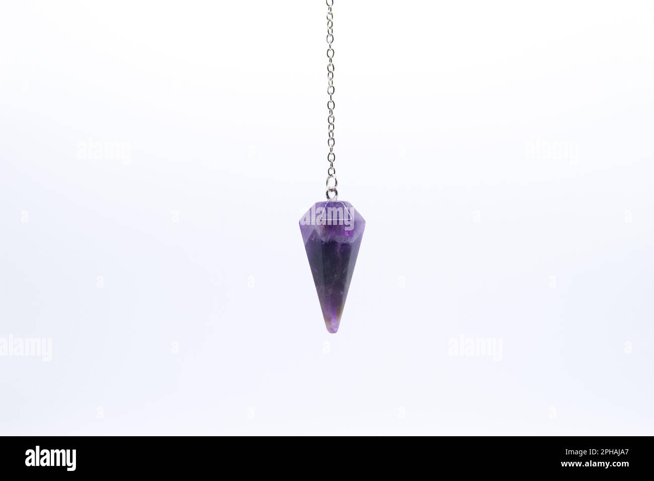 Purple Amethyst crystal pendulum on chain isolated on white background. Stock Photo