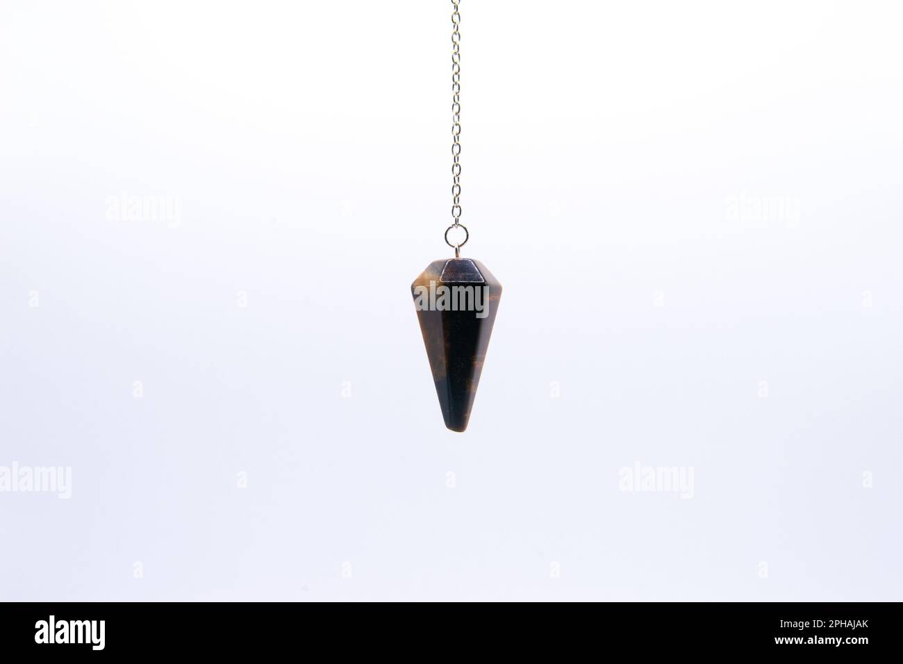 Tiger's eye crystal pendulum on chain isolated on white background. Stock Photo