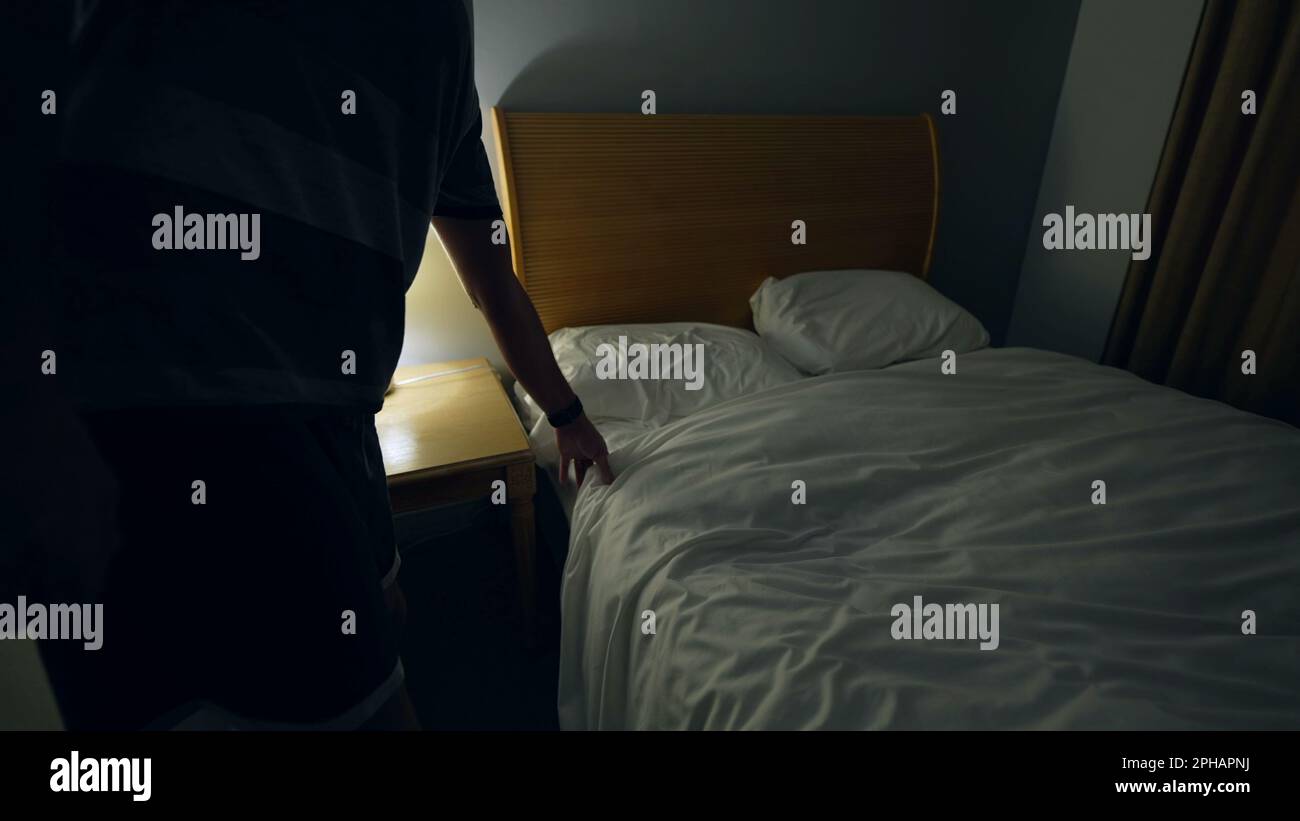 Man prepares to go to bed and sleep. Person lays down in bed and turns