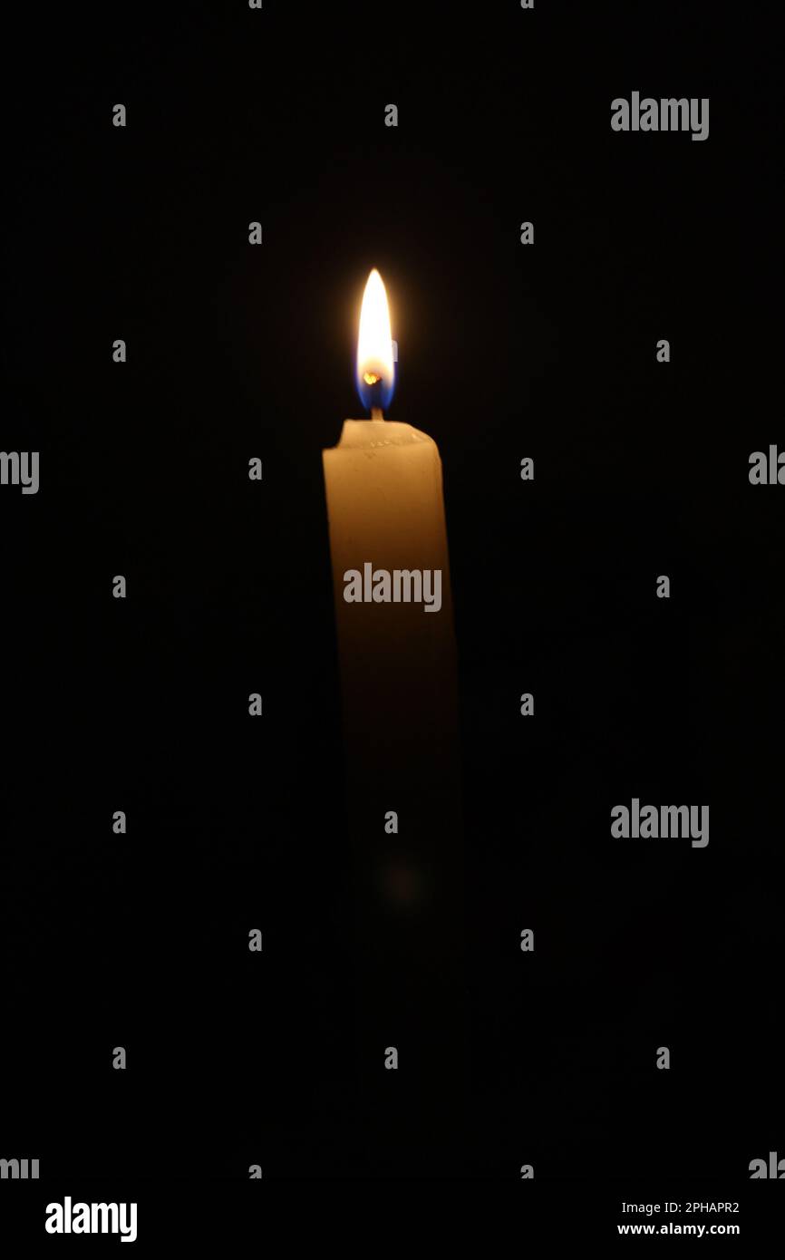 A lit candle in a dark environment, releasing a fragrant smoke into the