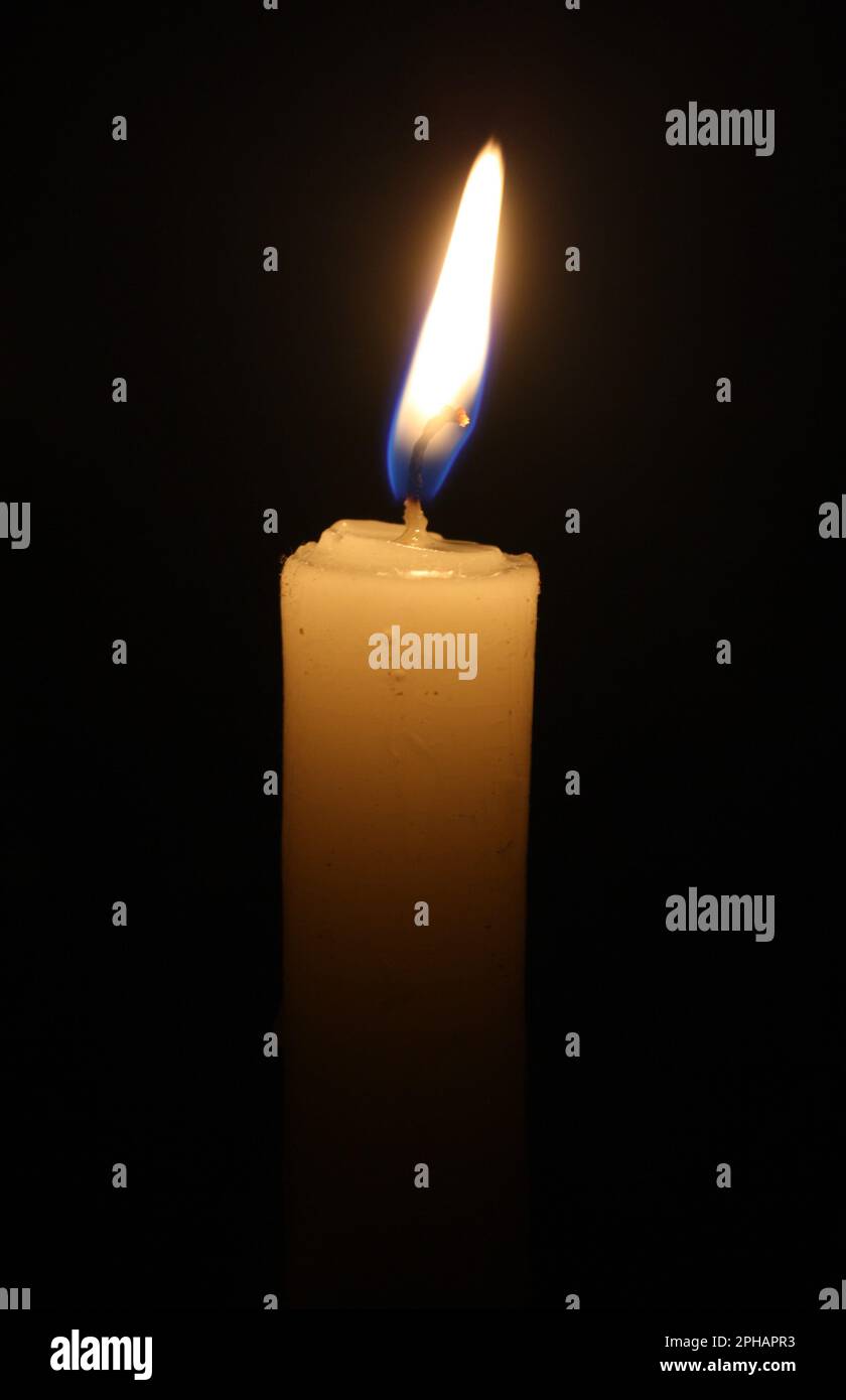 A solitary candle burning brightly in a dark room, providing a warm and