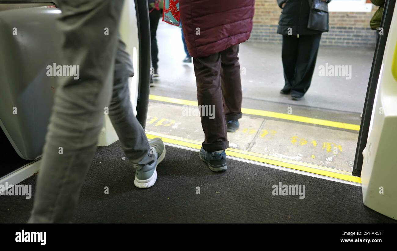 People leaving and entering subway train on platform. Close up legs on