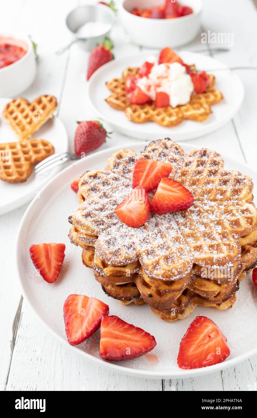Stacked waffles with strawberry topping on white table Stock Photo