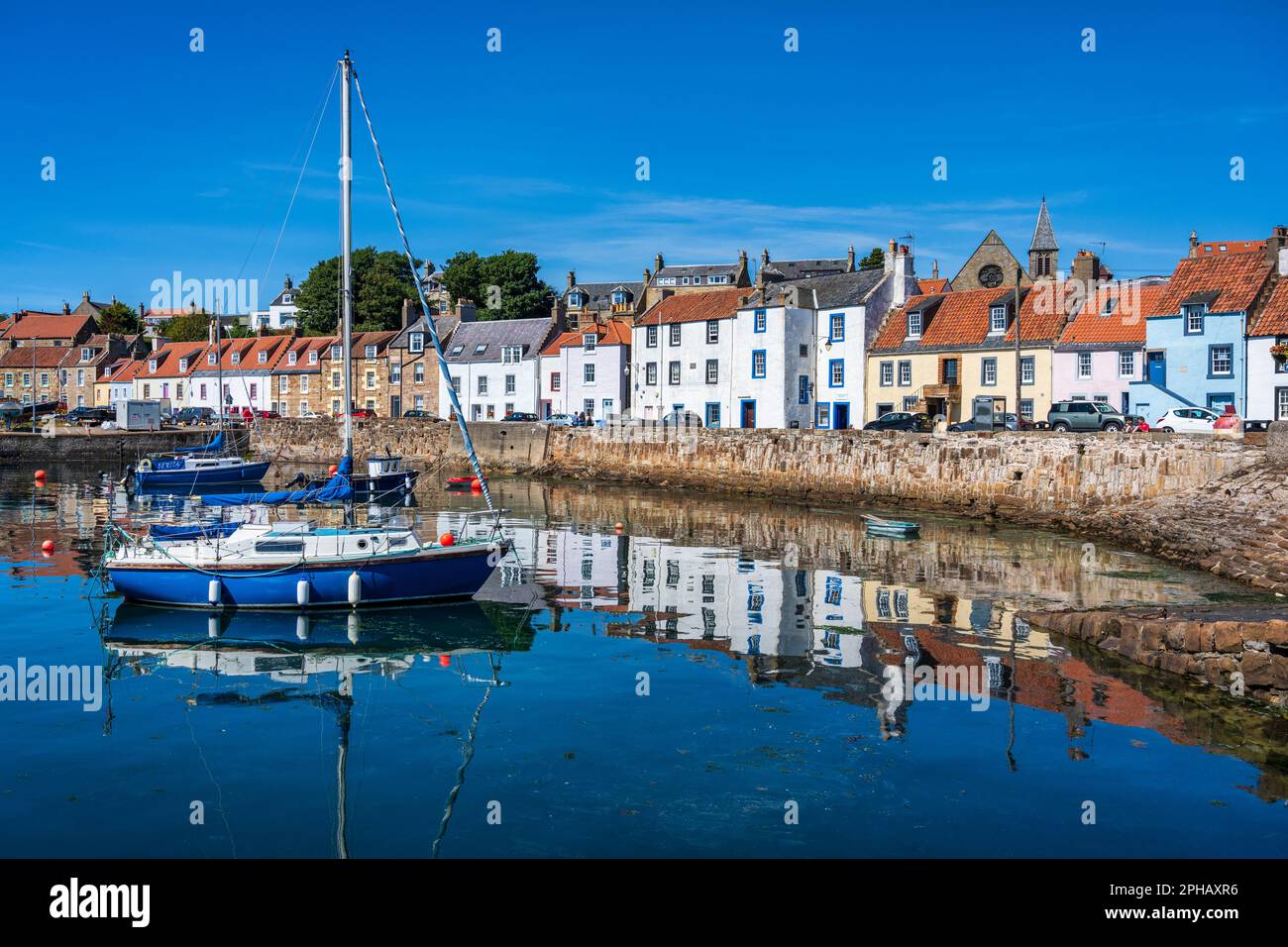 Yacht at anchor with colourful reflections of seafront houses at St
