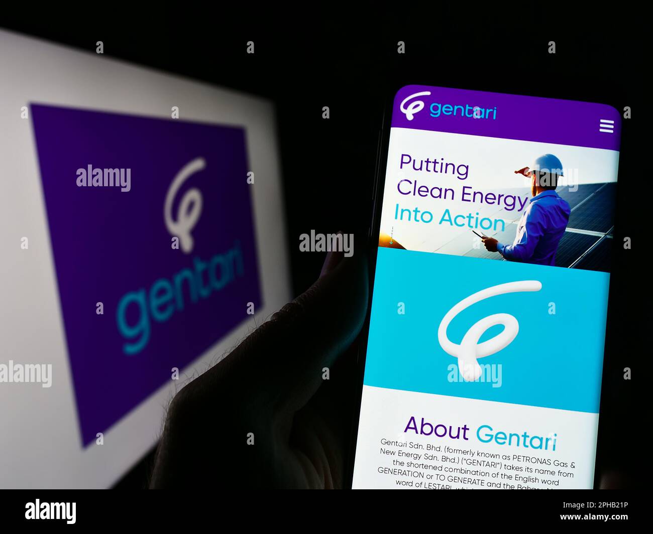 Person holding cellphone with webpage of Malaysian energy company Gentari Sdn. Bhd. on screen in front of logo. Focus on center of phone display. Stock Photo