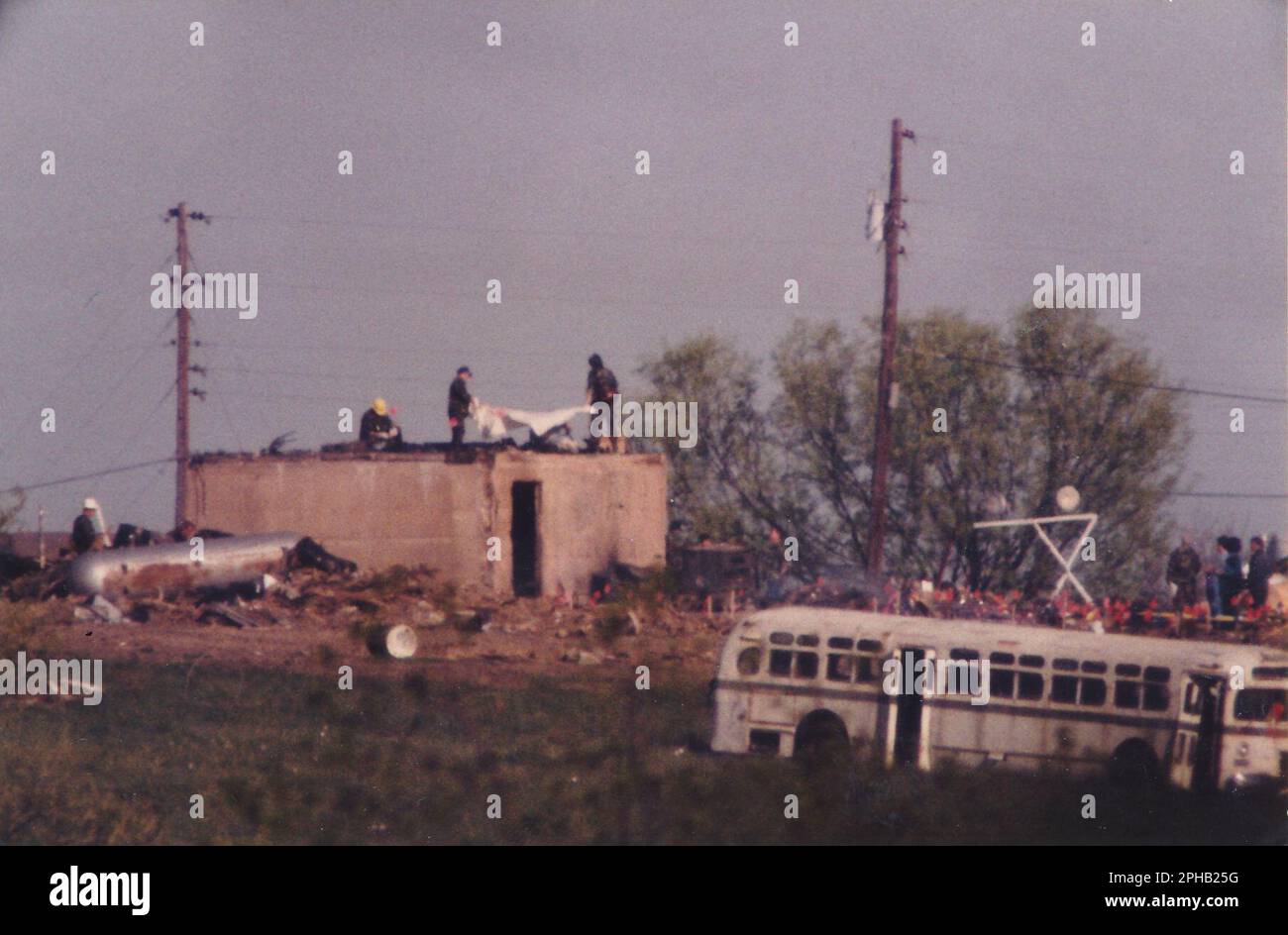 Waco, Texas USA, April 21, 1993: Federal agents load bodies into body bags on top of the bunker at the Branch Davidian compound two days after a devastating fire killed 76 members holed up at the religious cult's property and ended a 51-day standoff with federal law enforcement agencies. ©Bob Daemmrich Stock Photo