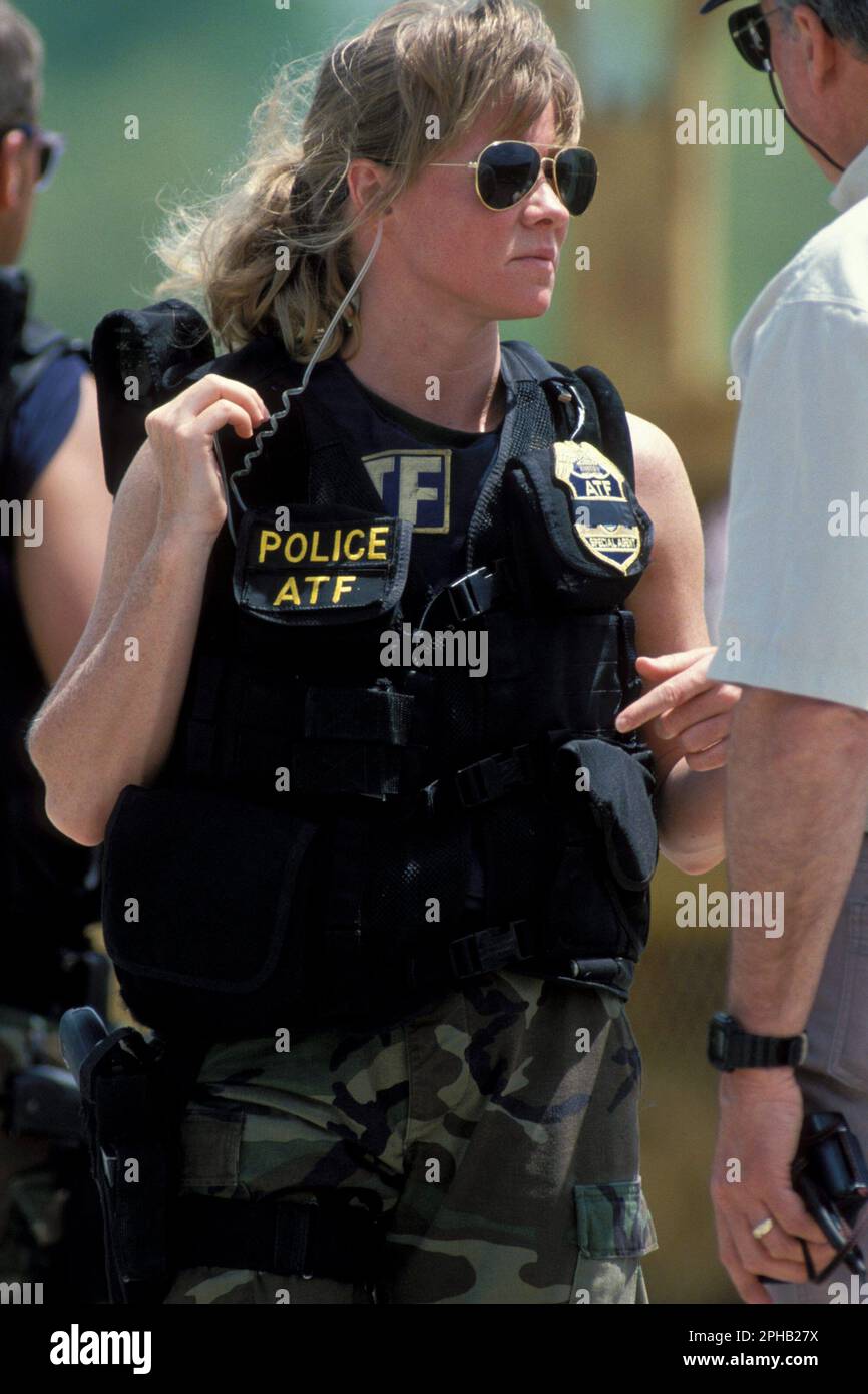 Waco, Texas USA, April 1993: Female agent in the Bureau of Alcohol, Tobacco and Firearms (ATF) wears a bulletproof vest and a communications earpiece is ready for action during the standoff between law enforcement agencies and the Branch Davidian religions group. ©Bob Daemmrich Stock Photo