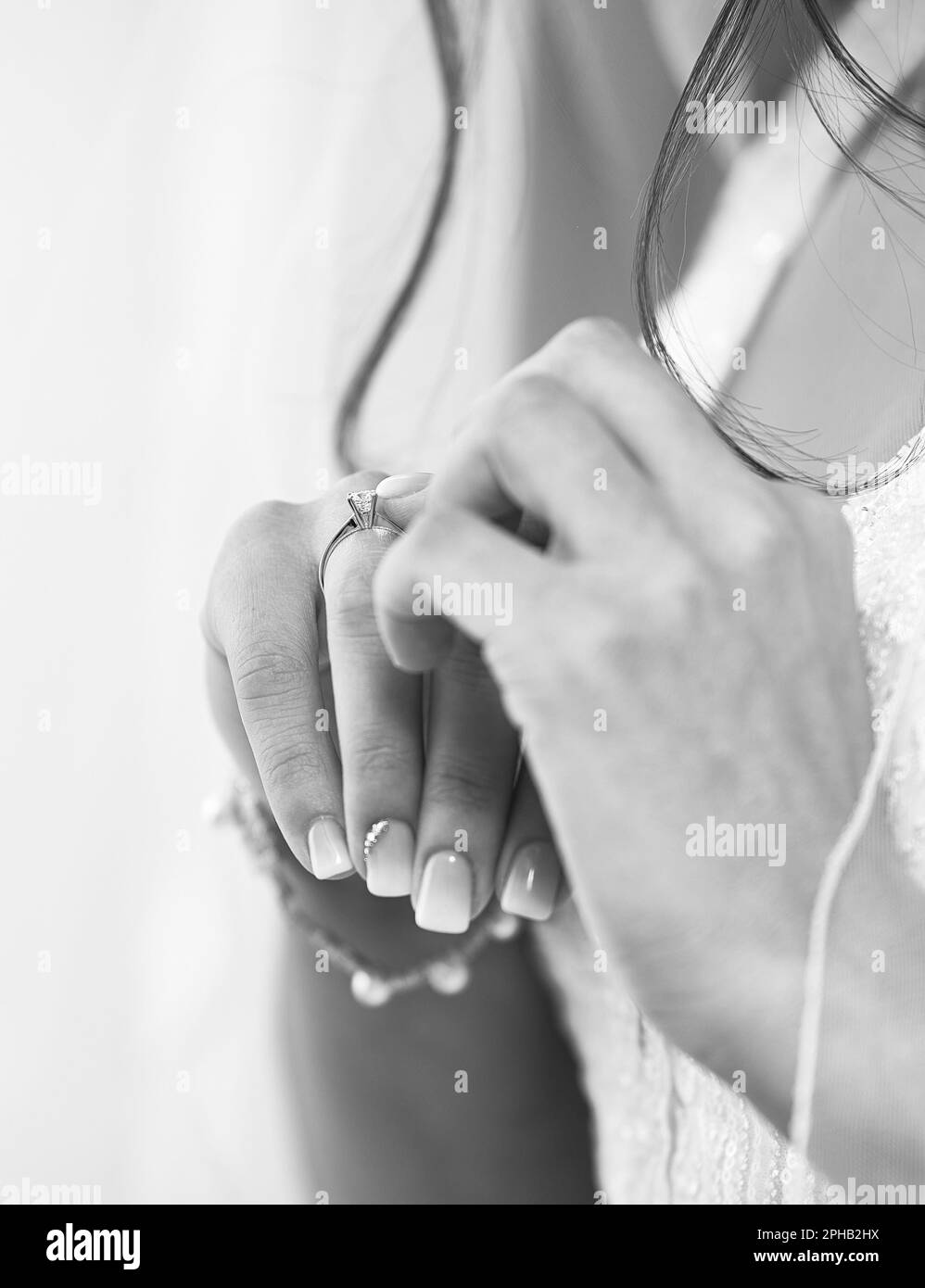 A grayscale closeup shot of a bride's hands clasped together. Stock Photo