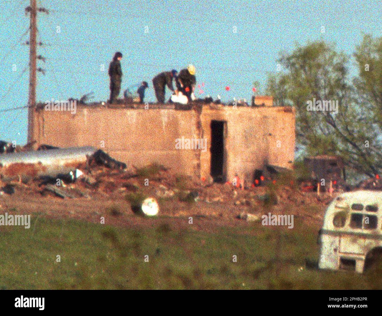 Waco, Texas USA, April 21, 1993: Federal agents load bodies into body bags on top of the bunker at the Branch Davidian compound two days after a devastating fire killed 76 members holed up at the religious cult's property and ended a 51-day standoff with federal law enforcement agencies. ©Bob Daemmrich Stock Photo