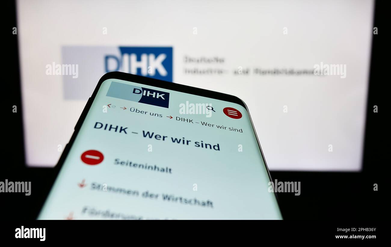 Mobile phone with webpage of Deutsche Industrie- und Handelskammer (DIHK) on screen in front of logo. Focus on top-left of phone display. Stock Photo